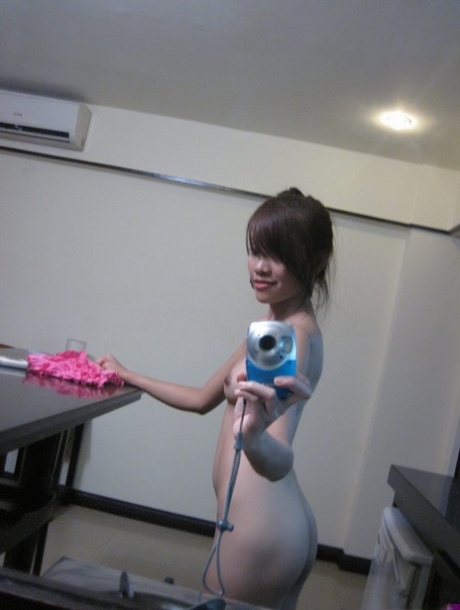 Cute teen Asian takes self shots in a mirror while getting naked