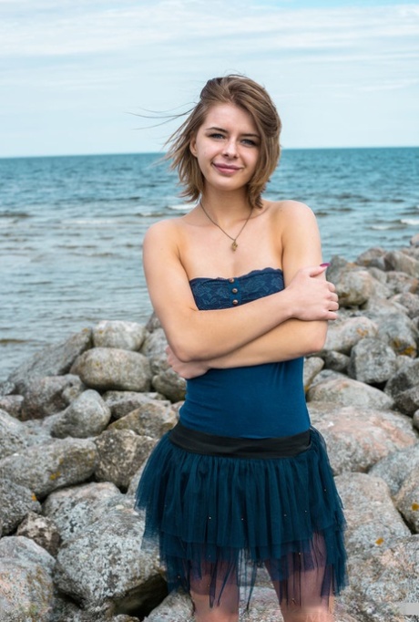 Teen girl reveals her big natural tits and hairless pussy on oceanside rocks