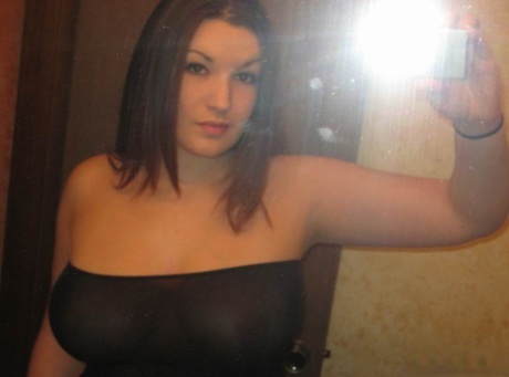 Curvy girl takes self shots in a mirror while wearing an off shoulder dress