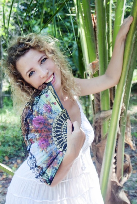 Teen solo girl with wavy blonde hair gets naked on a blanket near some ferns