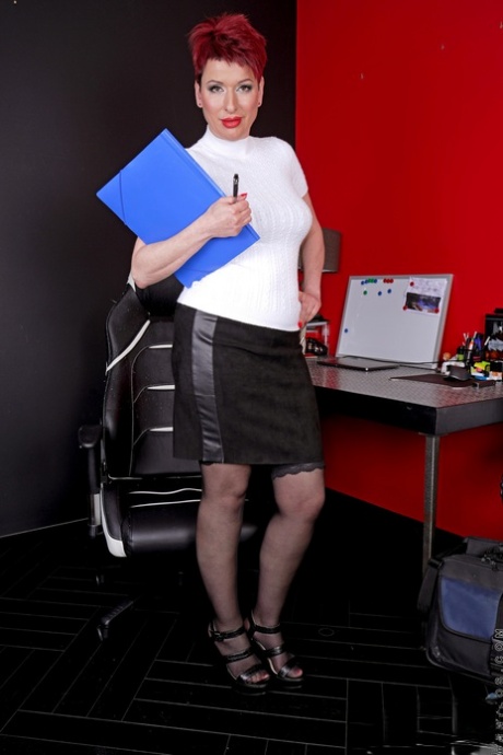 Redheaded businesswoman Lisa Pinelli uncovers her natural tits and bald pussy