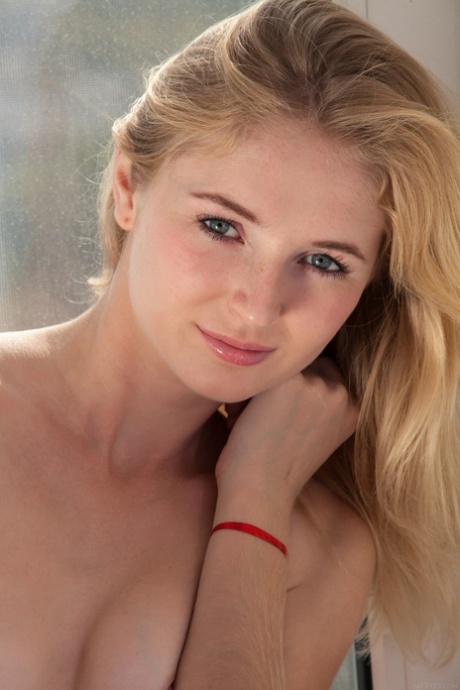 Petite blonde teen Leona Honey uncovers her tasty ass and poses in the window