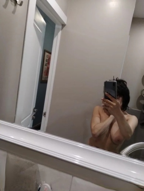 Mature brunette takes nude selfies in the bathroom showing her saggy tits
