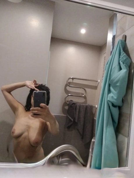 Mature brunette takes nude selfies in the bathroom showing her saggy tits