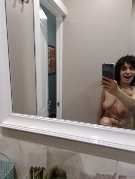 Mature brunette takes nude selfies in the bathroom showing her saggy tits