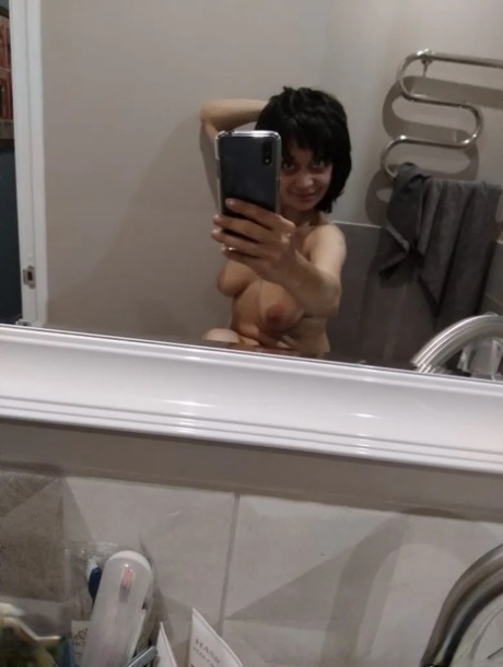 Mature brunette takes nude selfies in the bathroom showing her saggy tits
